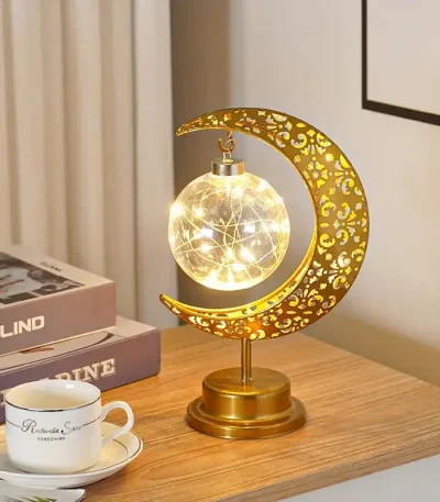 Dekorativ månlampa med stjärnfall, varm LED-belysning, elegant design i guldmetall, perfekt för inredning eller kontor.