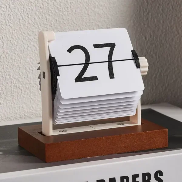 Vintage klockkalender i trä och plast, visar datum 27, retrodesign för kontors- eller inredningsdekoration.