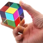 Färgglad Rubiks kub hålls mellan fingrarna på en hand, som illustrerar ett vetenskapligt tankespel och pussel.
