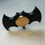 Batman nyckelring i metall med design av en svart fladdermus och guld mitt, perfekt för superhjältefans och inredning av kontor eller handväska.