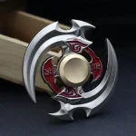Fidget spinner i metall med komplex design, mekaniska delar och röda detaljer, placerad på en mörk yta.