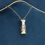 Halsband med vetenskaplig cylindrisk hänge, prytt med en gyllene metallstruktur, presenterat på en mörkblå bakgrund.