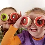 Två leende barn som bär färgglada observationsglasögon, utforskar världen med nyfikenhet och entusiasm, i en utbildande och lekfull miljö.