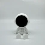 Miniatyrrobot i vit plast med svart ansikte, sittande på en vit yta, som framkallar vetenskap och teknologi.