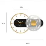 Modern väggklocka i guld- och svart metall, med en elegant och minimalistisk design, perfekt för samtida inredning.