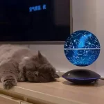 Jordglob som representerar en stjärnkarta och konstellationer, placerad på en träyta, med en sovande katt bredvid.