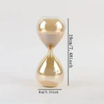 Transparent glas timer med beige sand, som mäter 19 cm hög och 8 cm bred, idealisk för vetenskaplig dekoration eller som ett originellt kontorsobjekt.