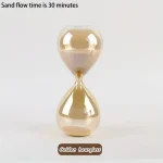 Guld sandbalanserare i glas, som illustrerar ett sandflöde på 30 minuter.
