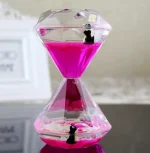 Dekorativt hänge i form av en diamant som innehåller en rosa vätska med två små plastpingviner inuti.