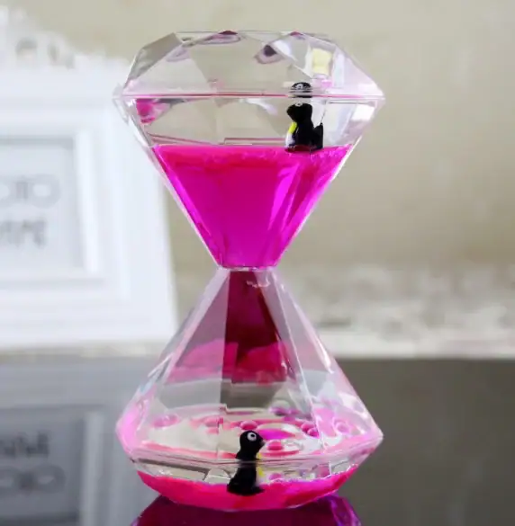 Dekorativt hänge i form av en diamant som innehåller en rosa vätska med två små plastpingviner inuti.