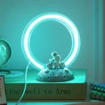 Vetenskaplig dekorationlampa med blått ljusring och dinosauriefigur på en månens bas.