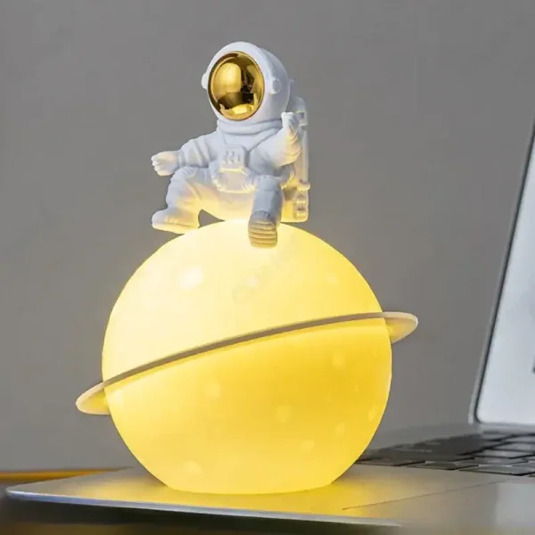 Dekorativt rymdskepp med astronaut i vit dräkt och gyllene hjälm, placerad på en lysande gul planet, idealisk för vetenskaplig eller tematisk dekoration.