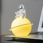 Miniatyr astronautdräkt placerad på en lysande planet med ring, science fiction-dekor.