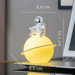 Dekorativ lampa i form av ett rymdskepp med en lysande astronaut, idealisk för vetenskaplig och modern inredning.