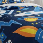 Sängkläder med rymdmotiv för barn, som illustrerar planeter, stjärnor, raketer och astronauter, perfekta för ett vetenskapligt eller astronomiskt tema.