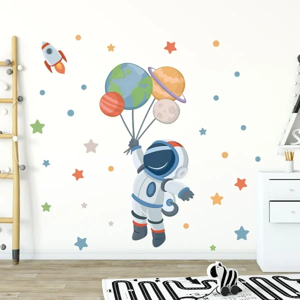 En astronaut i rymddräkt svävar i en väggdekoration med ballongplaneter, stjärnor och raket, vilket skapar en lekfull och lärorik atmosfär med rymdtema.