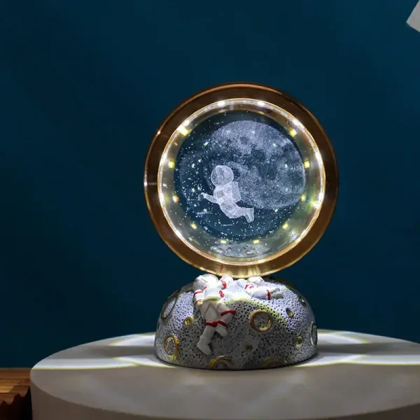 Dekorativ snöglob som föreställer en astronaut svävande i rymden, med en stjärnig bakgrund och inbyggd LED-belysning. Perfekt för vetenskaps- och originell inredning.