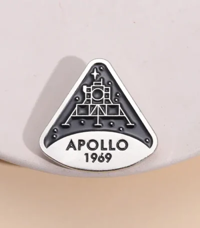 En brosch eller märke som föreställer NASA:s Apollo 11-mission, med datumet 1969, en ikonisk symbol för rymdutforskning.