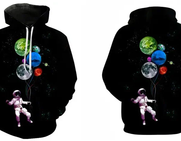 Svart huvtröja med ett rymdmotiv, som inkluderar en astronaut som svävar i rymden med färgglada planeter, idealisk för vetenskaps- och astronomiälskare.
