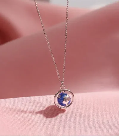 Halsband med miniatyrhäng av jordklot i silver, symbol för resa och upptäckter.