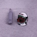Grå USB-sticka bredvid ett märke som föreställer en sovjetisk astronaut med hjälm och CCCP-logotyp.