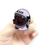 Astronautpin med sovjetisk logotyp och hundhuvud.