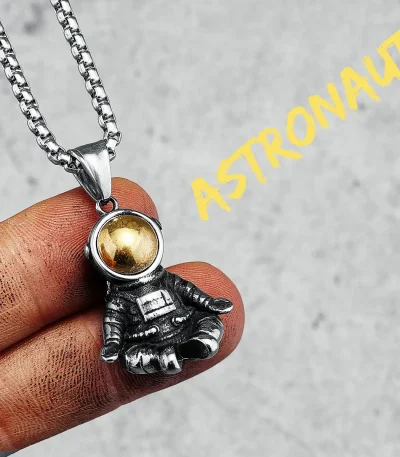 Halsband med astronauthäng i försilvrad metall och gyllene kula, inspirerat av rymden och rymdutforskning.