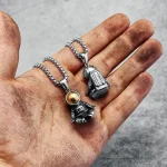 Astronauthäng i försilvrad metall, hängande på en kedja, placerade på en smutsig hand. Idealisk för vetenskaps- och astronomientusiaster.