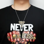 Vetenskapligt hänge i form av ett kranium och en knuten näve med inskriptionen "BOSS" i gyllene bokstäver, bärs med en kedja i försilvrad metall.