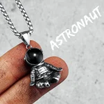 Astronauthäng i metall med svart kula, hängande på en kedja i rostfritt stål, idealiskt för astronomientusiaster och vetenskap.