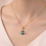 Hängsmycke av Saturnus i guld med stjärna och ädelstenar, symbol för astronomi och universum, perfekt för vetenskaps- och kosmisk dekorationsälskare.
