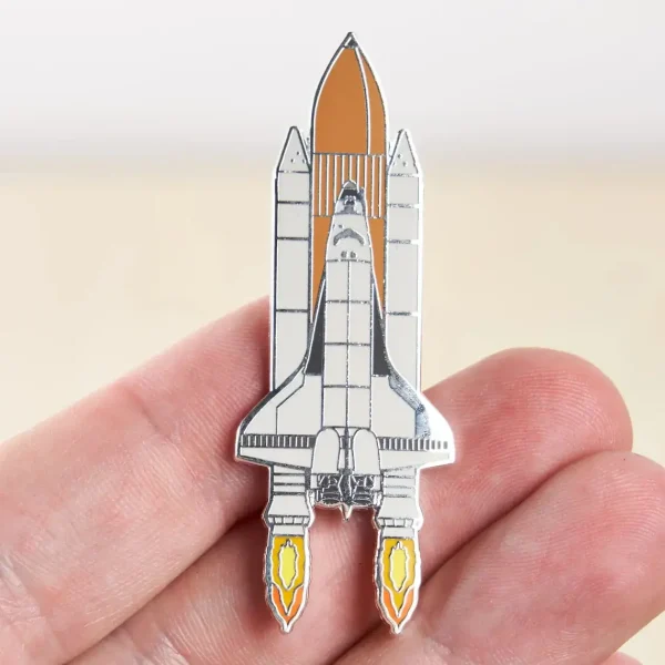 Pin i form av en rymdfarkost med metalldetaljer, som illustrerar en raket redo att lyfta, perfekt för astronomi- och vetenskapsentusiaster.