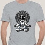 Grå t-shirt med illustration av sittande astronaut framför ett komplext geometriskt mönster, modern och vetenskaplig konststil.
