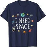 Blå t-shirt med rymdmotiv, planeter, astronauter, raket och texten "I NEED SPACE" för vetenskaps- och astronomientusiaster.