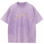 Lila T-shirt med mönster av månens faser i guld, avslappnad och trendig stil, perfekt för astronomi- och kosmisk designentusiaster.