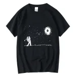 Svart T-shirt med motiv av astronaut som leker i rymden, observerar en galax och stjärnor, minimalistisk och konstnärlig design.