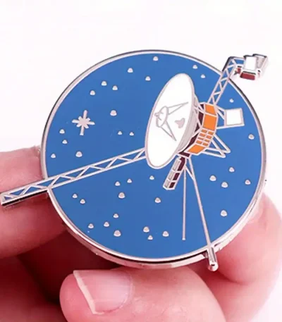 Dekorativ klocka i form av en satellit med blå urtavla och metalliska detaljer.
