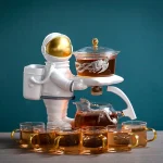 En vit plastastronaut med guldhjälm, som håller en bricka med en behållare med brun vätska, omgiven av flera glas med liknande vätska.
