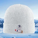 Vit ullkeps med broderi av en liten astronaut på en raket, idealisk för vetenskaps- och rymdutforskningsentusiaster.