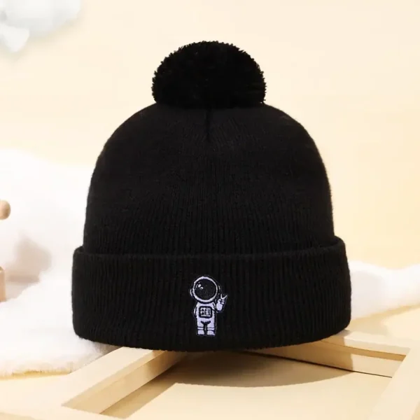 Svart ullmössa med pom-pom och astronautlogotyp, perfekt för vetenskaps- och astronomientusiaster, idealisk för vintern eller som vetenskaplig dekoration.