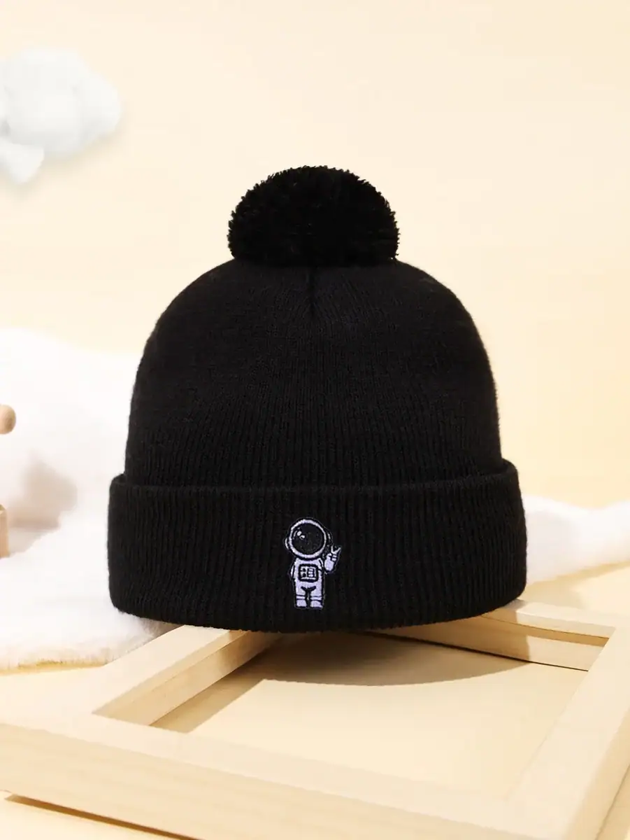 Svart ullmössa med pom-pom och astronautlogotyp, perfekt för vetenskaps- och astronomientusiaster, idealisk för vintern eller som vetenskaplig dekoration.