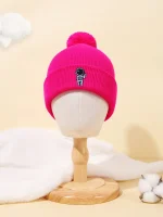 Rosa ullmössa med astronautbadge, varm och trendig accessoar för vintern, presenterad på en trämannequin i en mjuk och minimalistisk miljö.