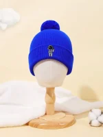 Blå ullmössa med ett litet broderat astronautmotiv, prydd med en pompom i ull. Perfekt för vetenskaps- och avslappnad stilentusiaster.