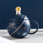 Dekorativ kopp i form av ett rymdskepp med en liten astronaut på toppen, dekorerad med planeter och stjärnor, idealisk för astronomientusiaster och vetenskaplig dekoration.