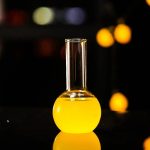 Laboratorievase i glas med en klar gul vätska, använd för vetenskapliga experiment eller som vetenskapsinspirerad dekoration.