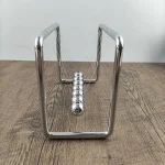 Glänsande Newtonpendel i metall, som illustrerar den berömda fysikaliska erfarenheten med hängande kulor, på en ljus träyta.