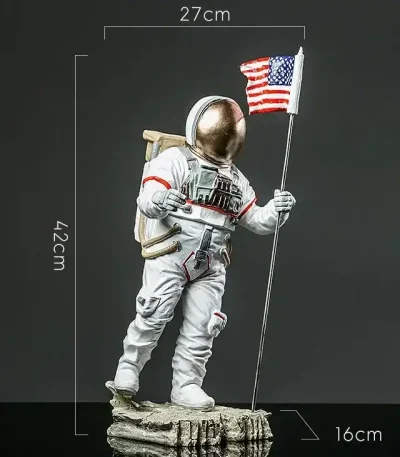 Astronautdräkt i figurform med amerikansk flagga, höjd 42 cm, mått 27x16 cm, som föreställer en rymdutforskare i full utrustning, stående på en stenig bas.