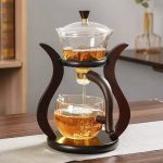 Te kopp i glas med infuser och trästöd, idealisk för att infusera teer eller infusioner, elegant och praktisk för en raffinerad smakupplevelse.