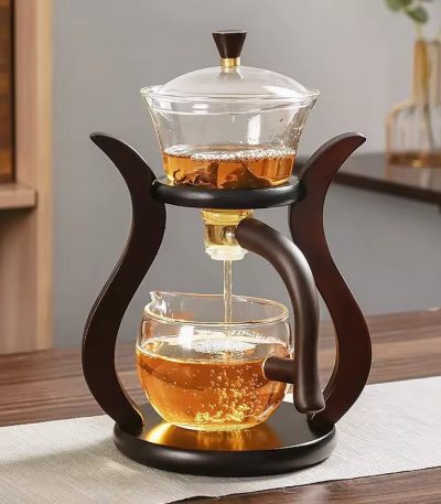 Te kopp i glas med infuser och trästöd, idealisk för att infusera teer eller infusioner, elegant och praktisk för en raffinerad smakupplevelse.