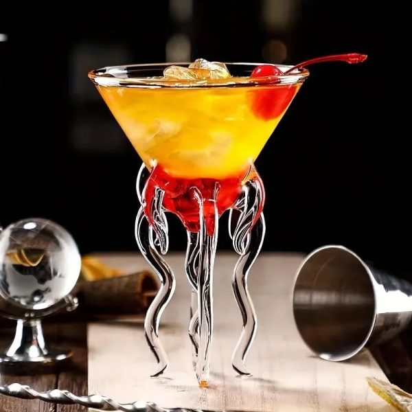 Vetenskapligt cocktailglas med dekoration i form av tentakler i transparent glas, fyllt med en gul-orange cocktail med körsbär, modern baratmosfär.